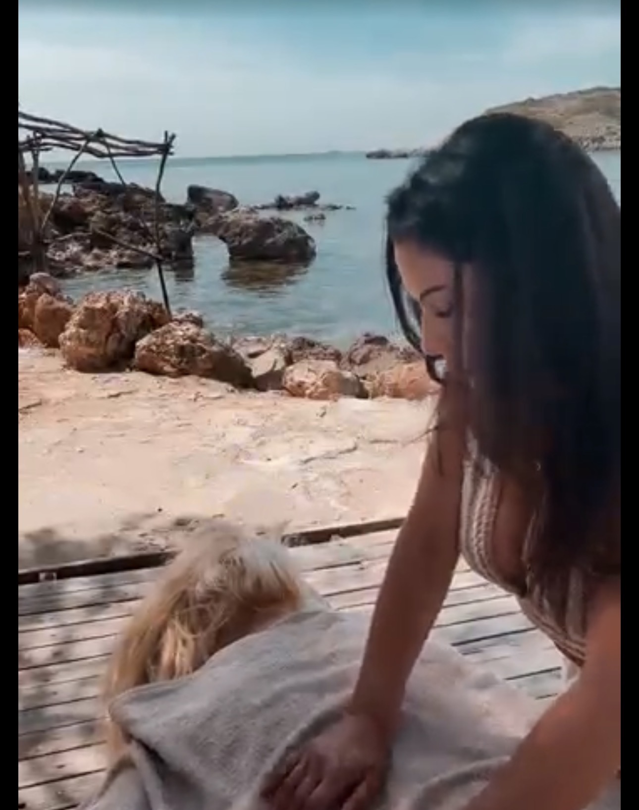 Parissa giving a massage on a wooden deck by the sea in Mallorca